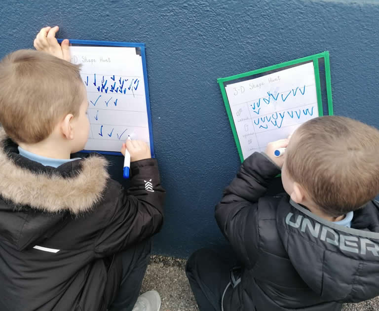 Boys writing on board outside